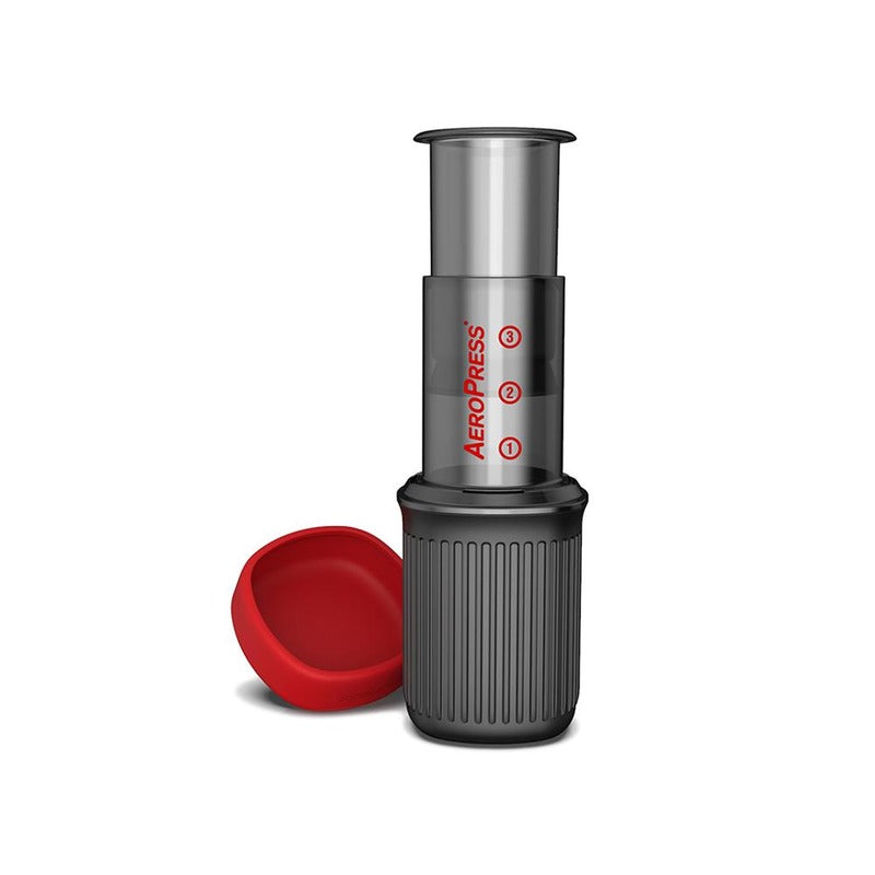 Assembled AeroPress Go brewer with the red lid placed beside the travel mug.