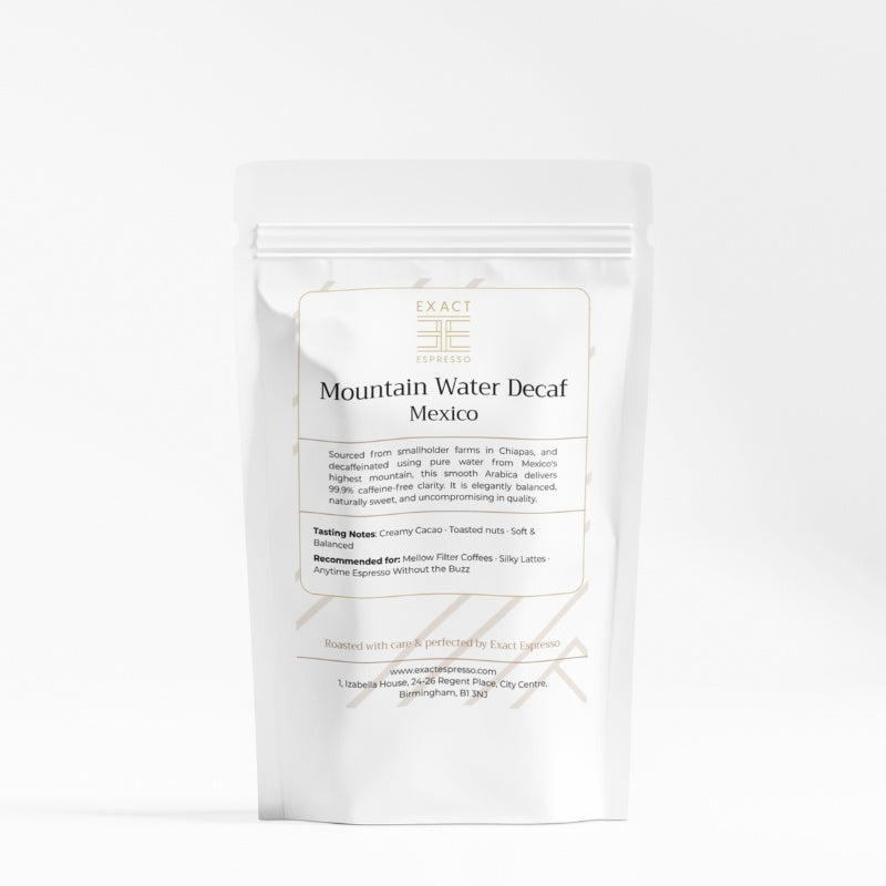 White coffee bag labeled "Mountain Water Decaf Mexico" from Exact Espresso, standing on a white background.