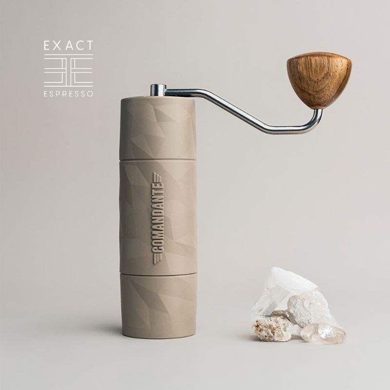 Beige Comandante X25 Trailmaster coffee grinder with wooden handle next to clear crystals.