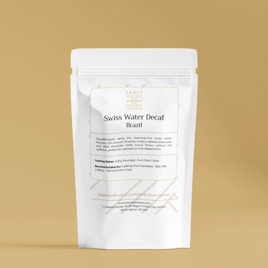 White coffee bag labeled “Swiss Water Decaf Brazil” with gold accents on gold background