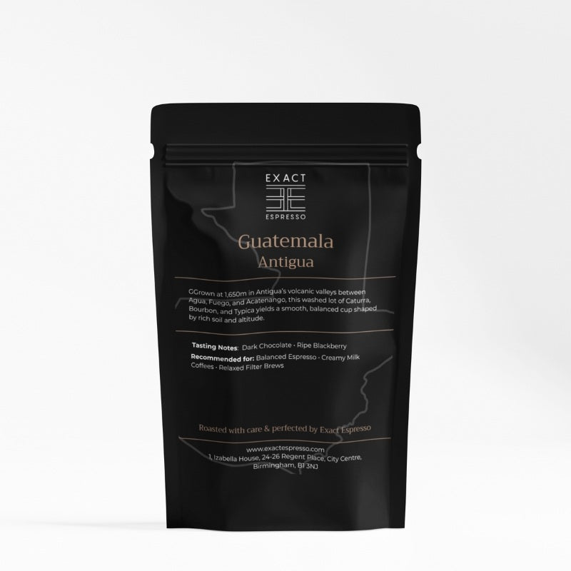 Black coffee bag labelled "Guatemala Antigua" from Exact Espresso, featuring tasting notes and origin details in copper lettering.