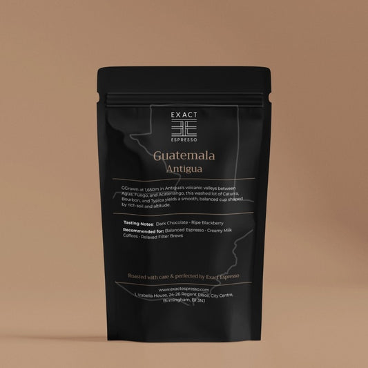 Exact Espresso's Guatemala Antigua coffee bag photographed on a warm beige background, displaying origin, tasting notes, and brewing suggestions.